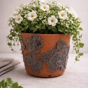 Handmade earthenware planter with raised floral design and deep blue glaze.